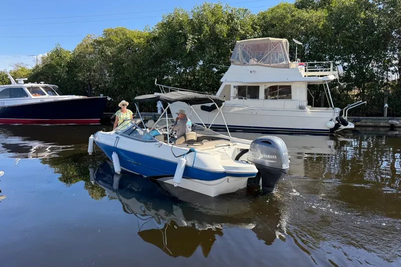 Slide: The Image of 2018 Stingray 204 LR boat on water, surrounded by other boats and greenery. - 2