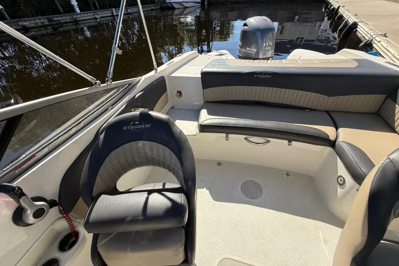 Slide: The Image of 2018 Stingray 204 LR boat interior with seating and steering wheel, docked by the water. - 21