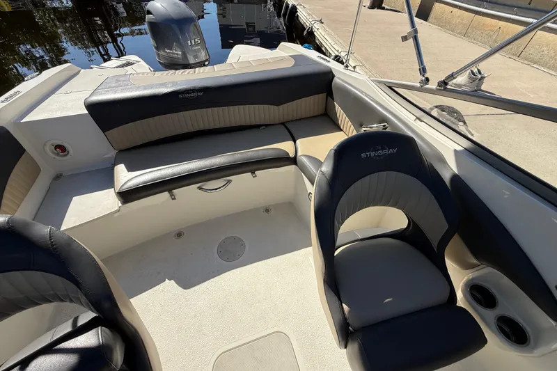 Slide: The Image of 2018 Stingray 204 LR boat interior with seating and motor, docked by the water. - 22