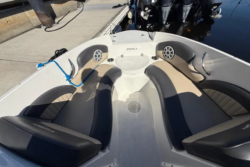 Slide: The Image of 2018 Stingray 204 LR boat interior with cushioned seating and speakers at dockside. - 25