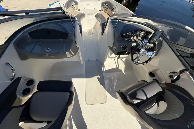 Slide: The Image of 2018 Stingray 204 LR boat interior with steering wheel and seating, docked by water. - 28