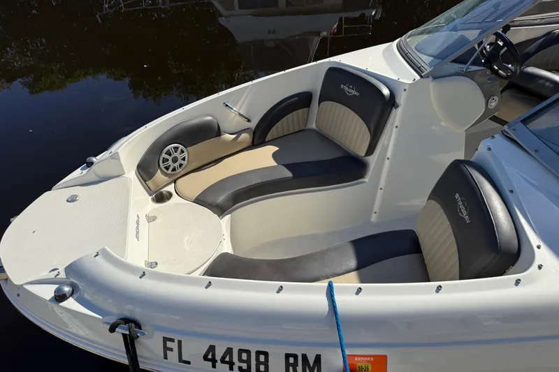Slide: The Image of 2018 Stingray 204 LR boat interior with seating and speaker, docked on calm water. - 5
