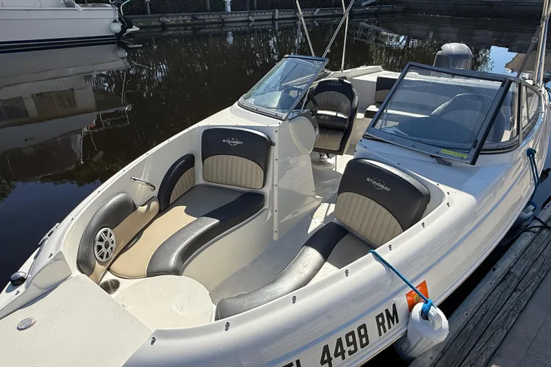 Slide: The Image of 2018 Stingray 204 LR boat with sleek seating, docked by the water. - 7