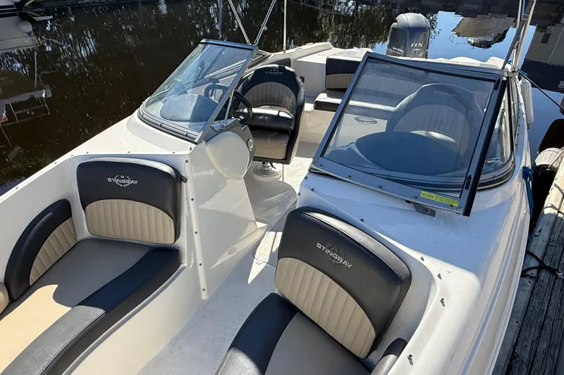 Slide: The Image of 2018 Stingray 204 LR boat interior with seating and steering wheel, docked by water. - 8