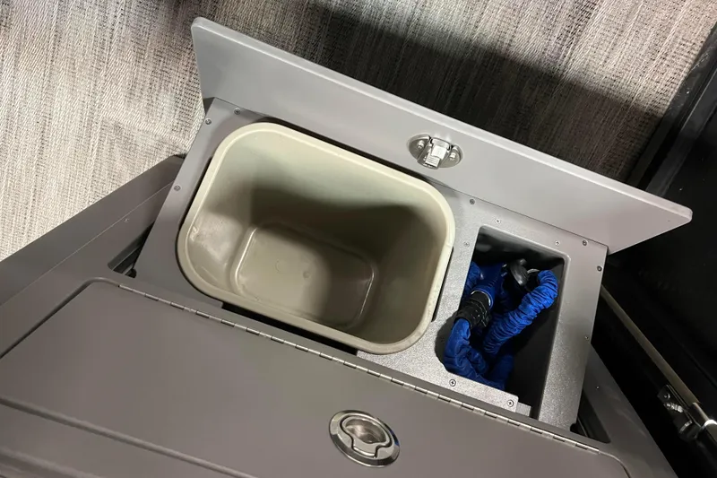 Slide: The Image of 2024 Angler Qwest 8522 LTZ FISH N SKI storage compartment with open lid and accessories. - 16