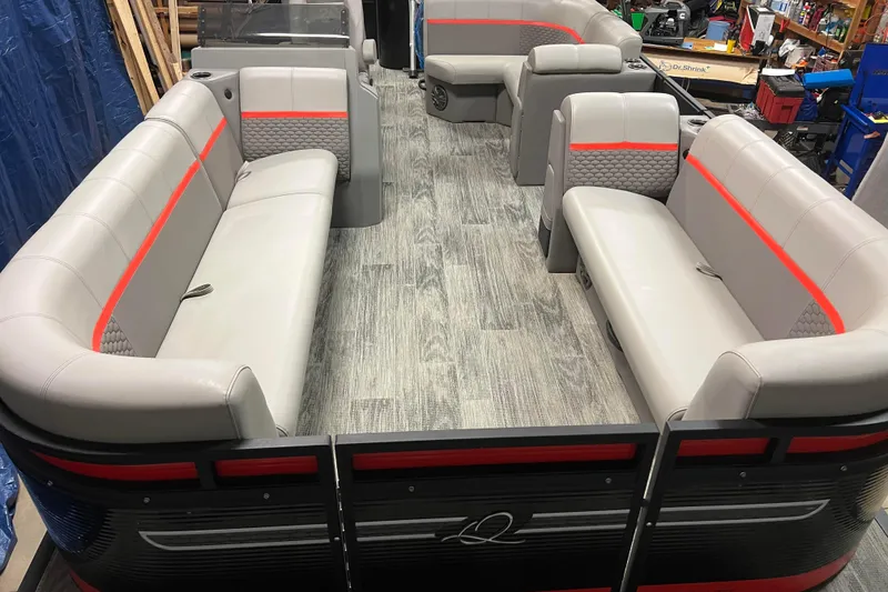 Slide: The Image of 2024 Angler Qwest 8522 LTZ FISH N SKI pontoon boat interior with gray and red seating. - 2