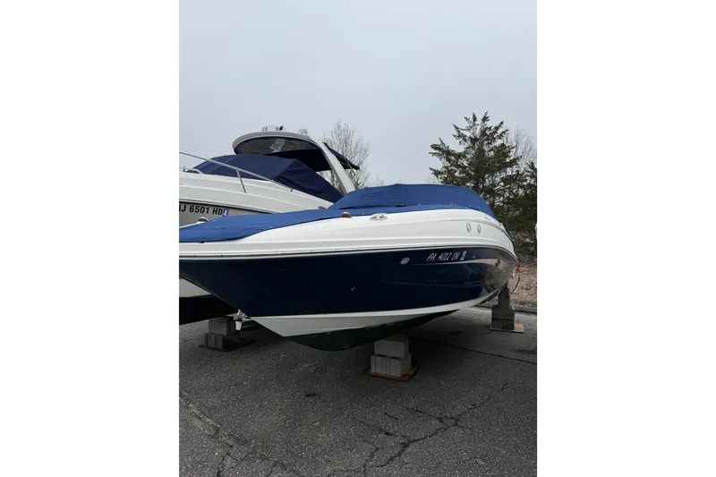 Slide: The Image of 2012 Sea Ray 240 Sundeck boat on blocks, covered, in a parking area. - 15