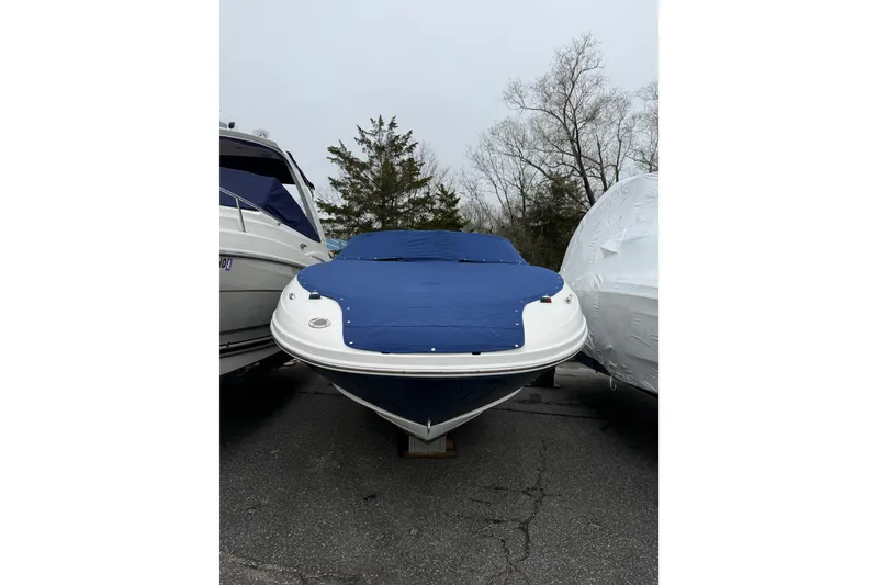 Slide: The Image of 2012 Sea Ray 240 Sundeck boat with blue cover, parked outdoors. - 16