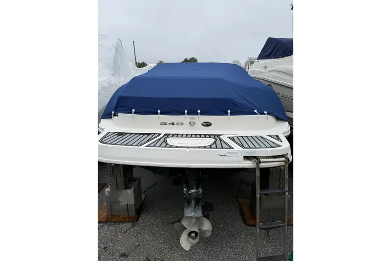 Slide: The Image of 2012 Sea Ray 240 Sundeck boat with blue cover, docked on land. - 19