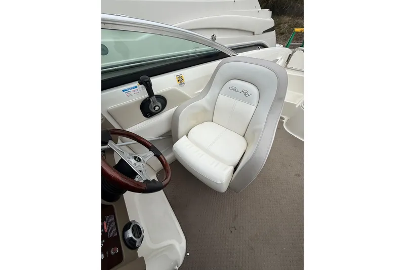 Slide: The Image of 2012 Sea Ray 240 Sundeck interior with white captain's chair and steering wheel. - 32