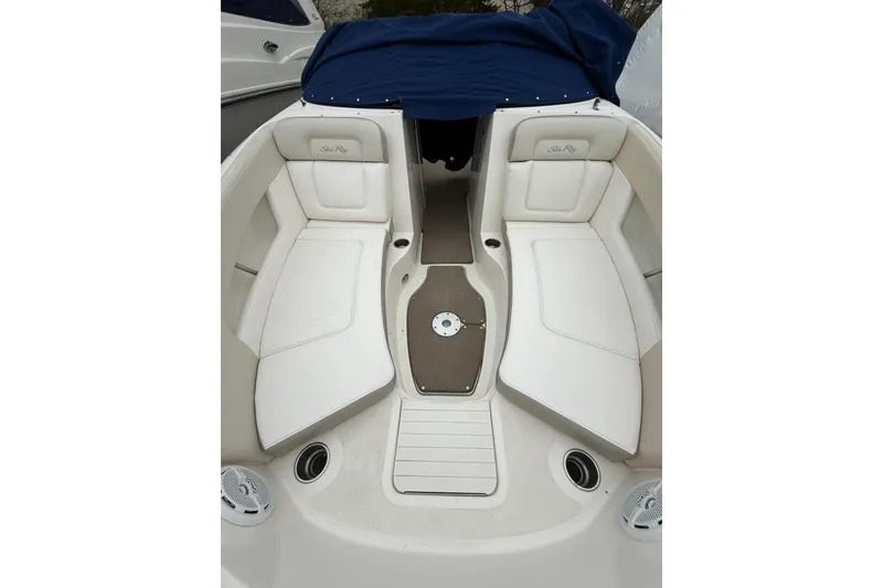 Slide: The Image of 2012 Sea Ray 240 Sundeck interior with white seating and blue cover. - 52