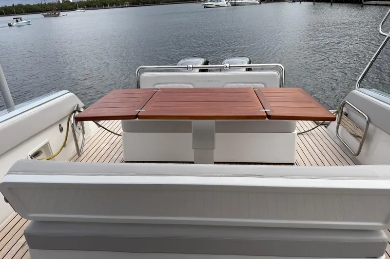 Slide: The Image of 2023 Schaefer V33 yacht interior with wooden table and seating, overlooking calm waters. - 12