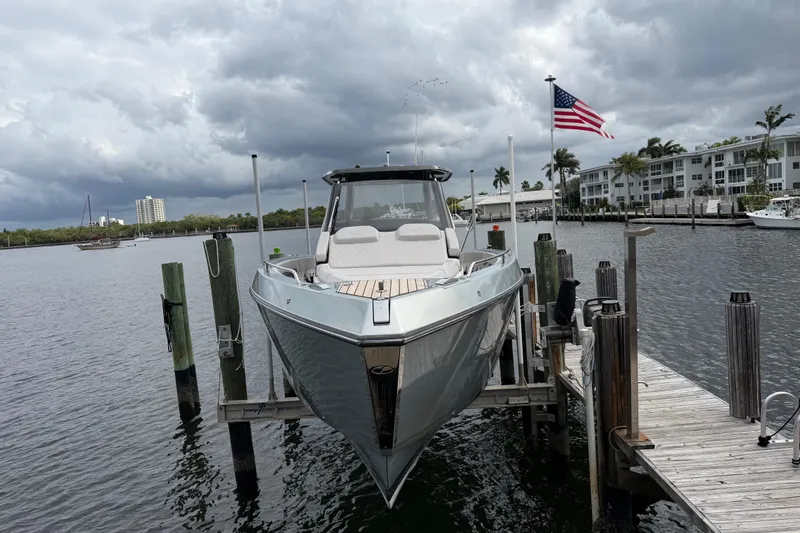 Slide: The Image of 2023 Schaefer V33 boat docked, cloudy sky, American flag, waterfront buildings. - 2
