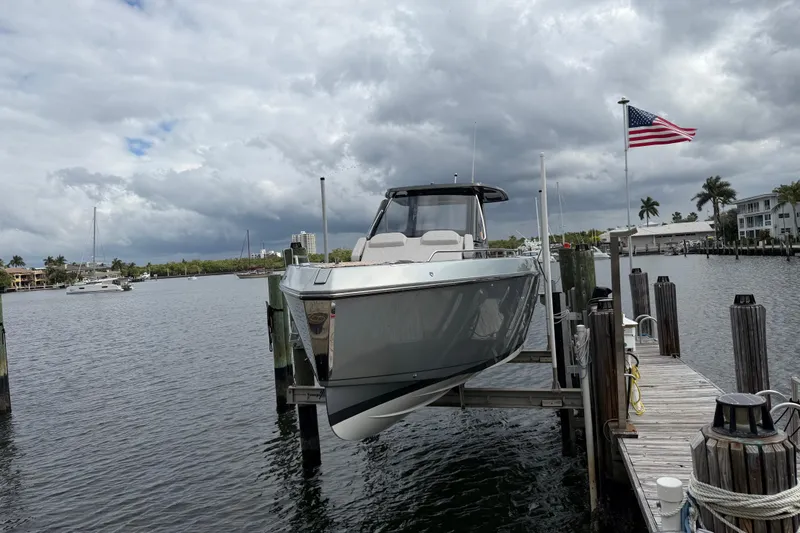 The Image of 2023 Schaefer V33 boat docked at marina with American flag, cloudy sky background. - 4