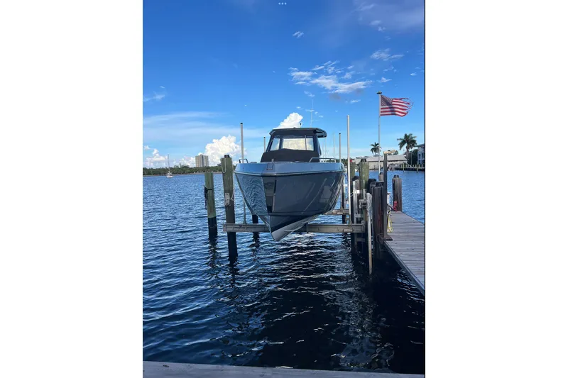 Slide: The Image of 2023 Schaefer V33 boat docked on a lift, with American flag and blue sky. - 5