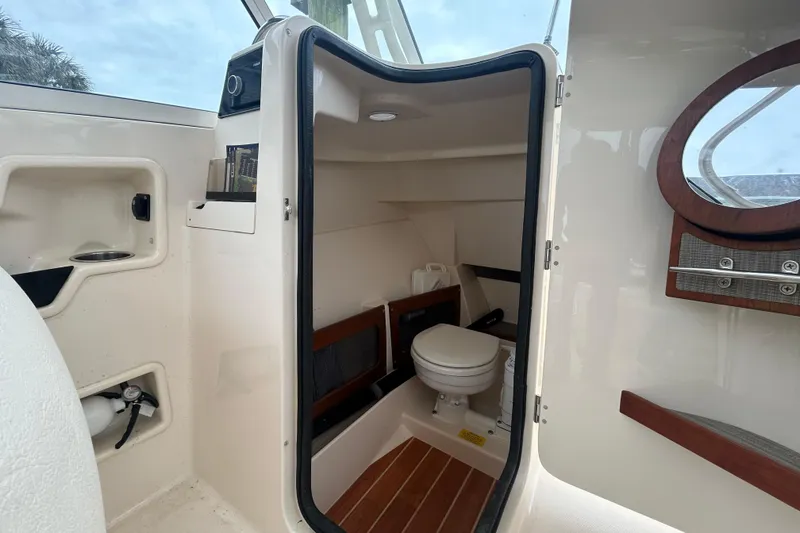 Slide: The Image of 2022 Grady-White Freedom 235 boat interior with compact marine toilet and storage. - 18