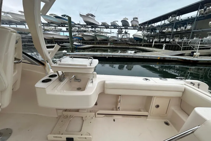 Slide: The Image of 2022 Grady-White Freedom 235 boat interior at marina with docked boats in background. - 8