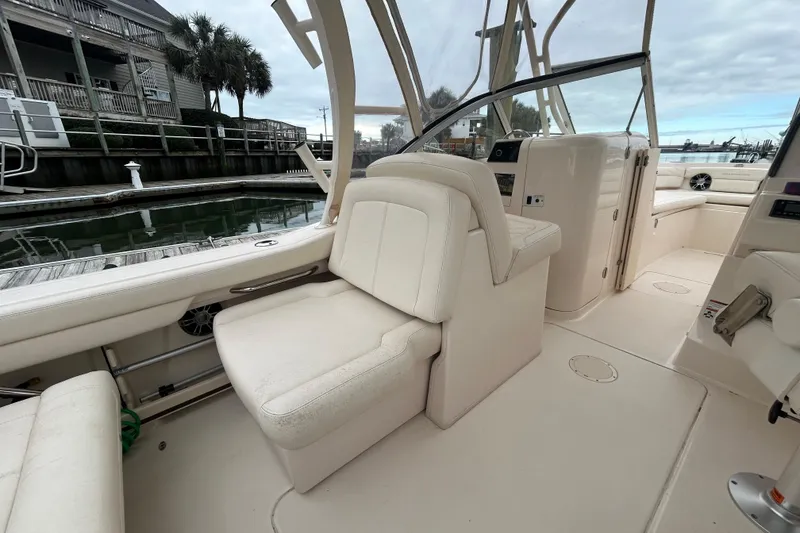 Slide: The Image of 2022 Grady-White Freedom 235 boat interior with seating and helm, docked at marina. - 9