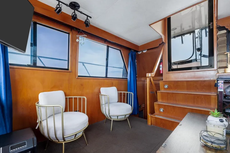 Slide: The Image of 1988 Marine Trader Trawler interior with modern chairs, wooden paneling, and large windows. - 13