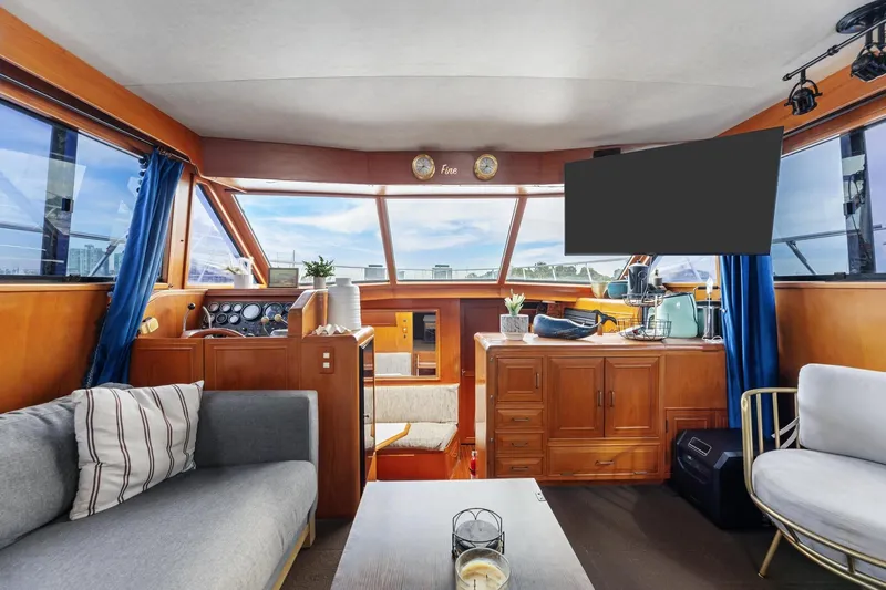 Slide: The Image of 1988 Marine Trader Trawler interior with cozy seating, wooden cabinetry, and large windows. - 14