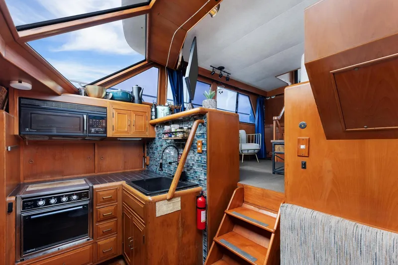 Slide: The Image of 1988 Marine Trader Trawler interior with wood cabinetry, kitchen appliances, and stairs leading to seating area. - 18
