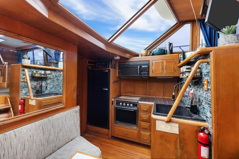 Slide: The Image of 1988 Marine Trader Trawler interior with wooden cabinetry, kitchen appliances, and skylight. - 19