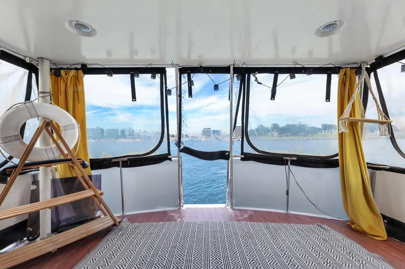 Slide: The Image of 1988 Marine Trader Trawler interior with panoramic water view, yellow curtains, and nautical decor. - 24