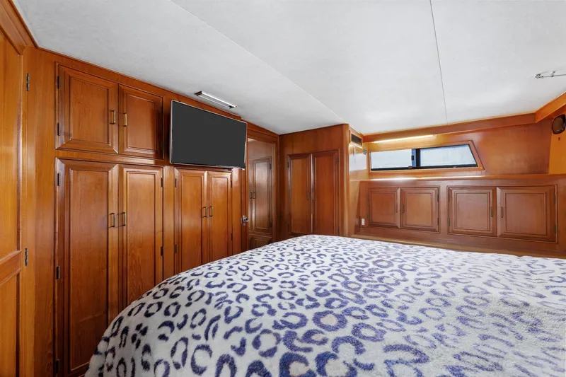 Slide: The Image of 1988 Marine Trader Trawler bedroom with wood paneling, TV, and patterned bedspread. - 31