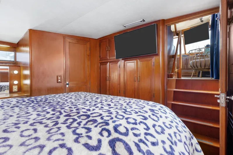 Slide: The Image of 1988 Marine Trader Trawler bedroom with wooden cabinetry and patterned bedding. - 32