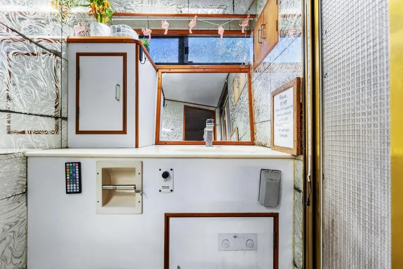 Slide: The Image of 1988 Marine Trader Trawler bathroom with mirror, cabinets, and remote control. - 34