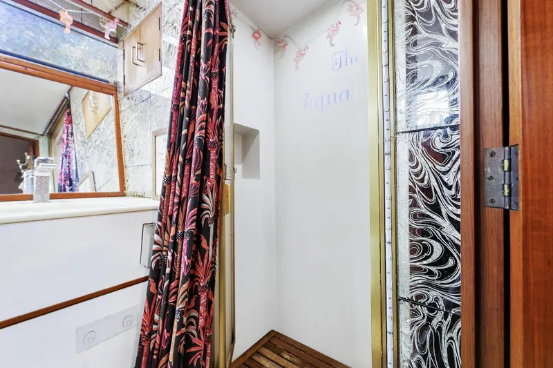 Slide: The Image of 1988 Marine Trader Trawler bathroom with decorative shower curtain and wooden accents. - 37