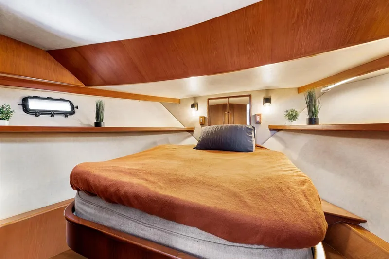 Slide: The Image of 1988 Marine Trader Trawler cabin with cozy bed, wooden accents, and porthole window. - 38