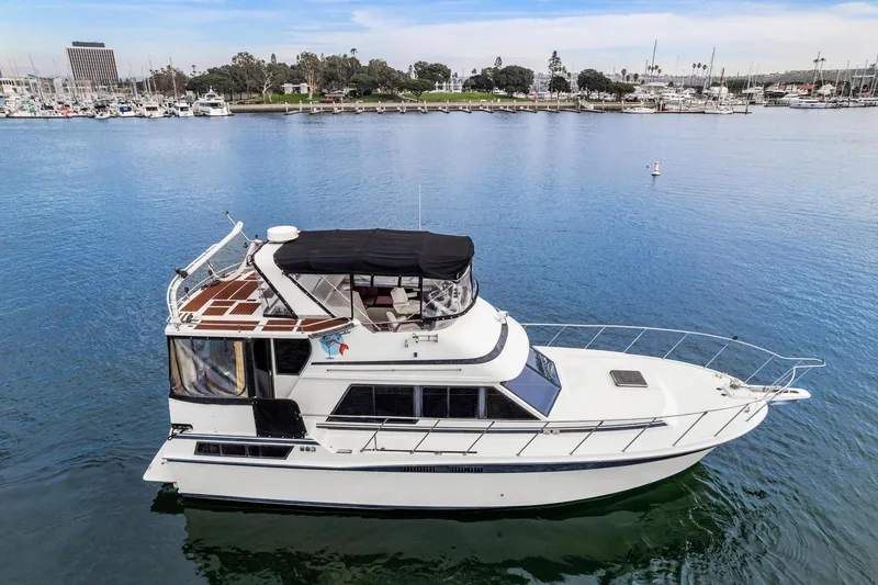 Slide: The Image of 1988 Marine Trader Trawler on calm water near marina, showcasing classic design and spacious deck. - 4