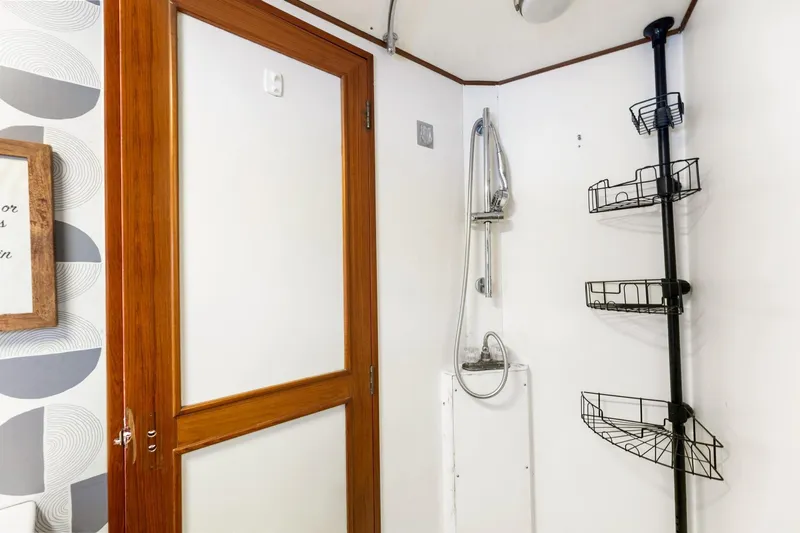 Slide: The Image of 1988 Marine Trader Trawler bathroom with shower, wooden door, and corner storage shelves. - 43
