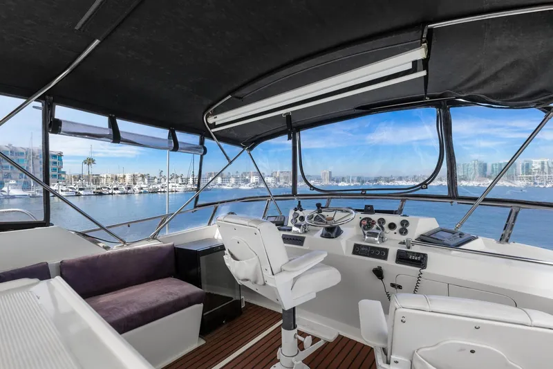 Slide: The Image of 1988 Marine Trader Trawler helm with marina view, featuring navigation equipment and seating. - 44