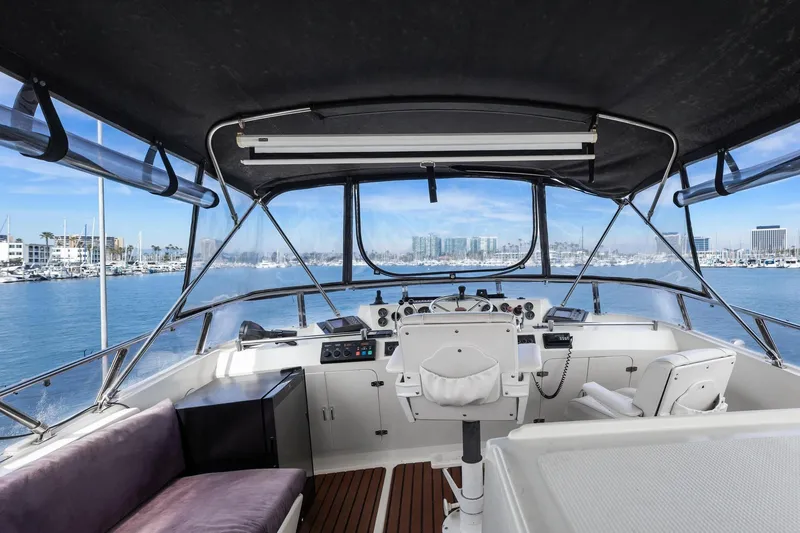 Slide: The Image of 1988 Marine Trader Trawler helm with marina view, featuring navigation controls and seating. - 50