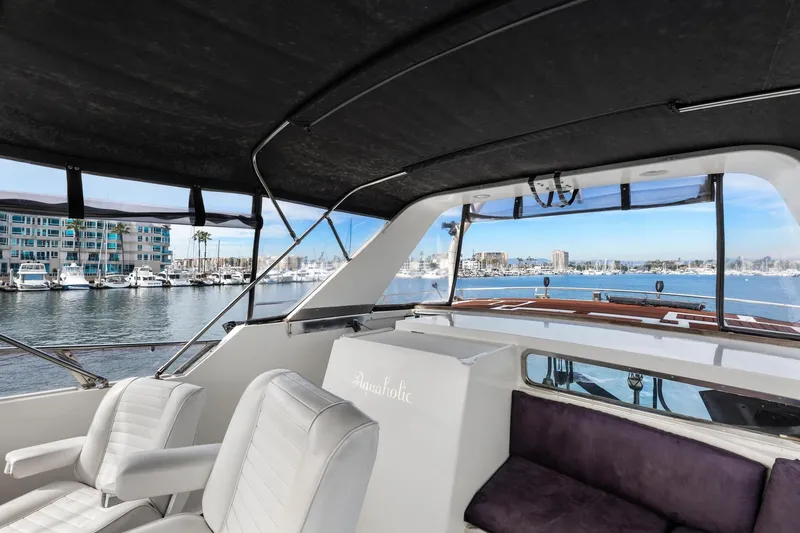 Slide: The Image of 1988 Marine Trader Trawler interior with marina view, featuring white seating and a covered deck. - 54