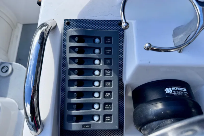 Slide: The Image of Control panel on 2023 Novurania Catamaran 20, featuring various switches and steering components. - 15