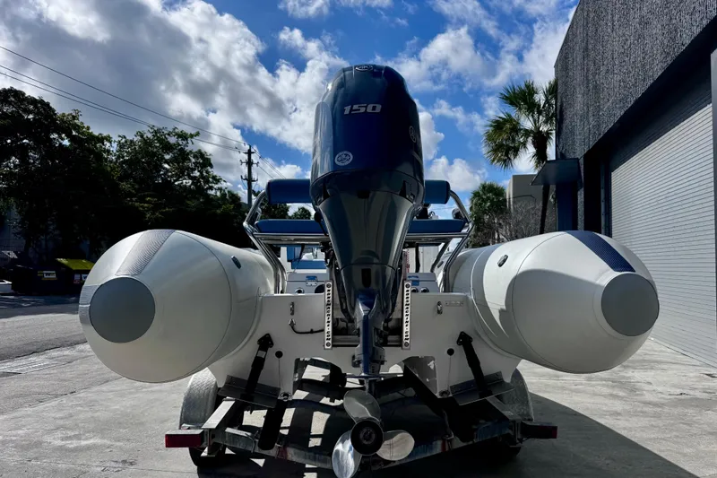 Slide: The Image of 2023 Novurania Catamaran 20 with 150 HP engine, parked outdoors under a cloudy sky. - 3