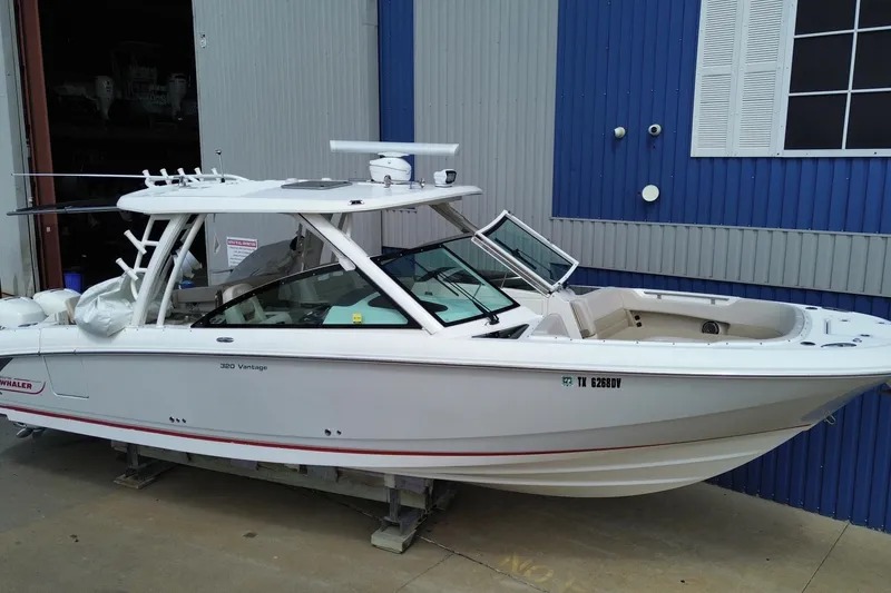 Slide: The Image of 2017 Boston Whaler 320 Vantage boat docked near a blue and gray building. - 2