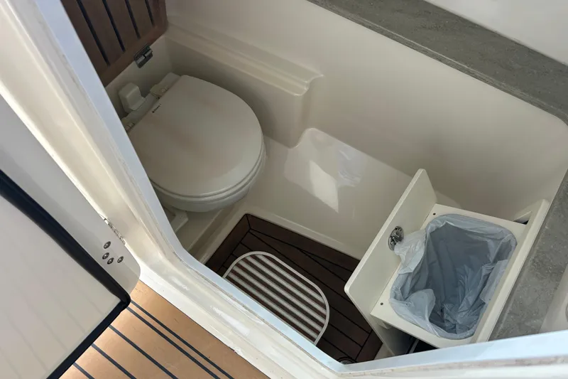 Slide: The Image of 2017 Boston Whaler 320 Vantage boat bathroom with toilet and trash bin. - 32