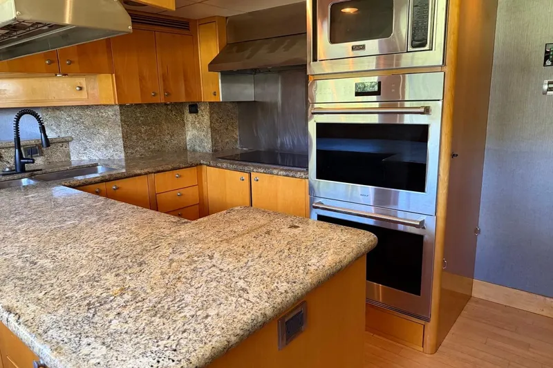 Slide: The Image of Modern yacht kitchen with granite countertops, stainless steel appliances, and wooden cabinetry on a 1990 Heesen 144. - 109