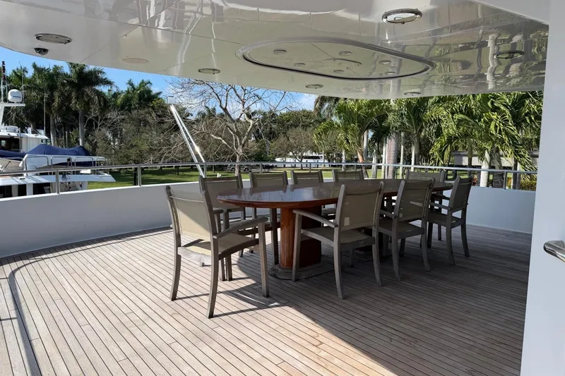 Slide: The Image of Outdoor dining area on 1990 Heesen 144 yacht with wooden deck and tropical surroundings. - 17