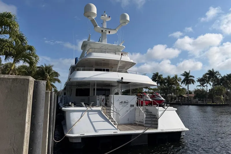 Slide: The Image of Luxury Heesen 144 yacht docked, 1990 model, with jet skis, surrounded by palm trees. - 3