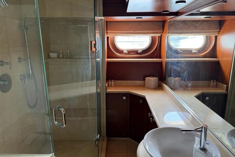 Slide: The Image of Luxurious yacht bathroom with glass shower, porthole windows, and elegant wood cabinetry. Heesen 144, 1990. - 67