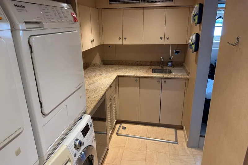 Slide: The Image of Laundry room with stacked Miele appliances, beige cabinets, and granite countertops on a Heesen 144 yacht. - 83