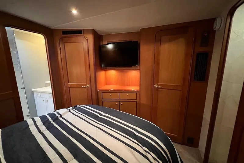 Slide: The Image of Luxurious bedroom in 2002 Ocean Yachts 56 Super Sport with striped bedding and TV. - 22