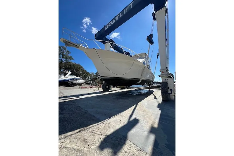 Slide: The Image of 2002 Ocean Yachts 56 Super Sport lifted by boat hoist under clear blue sky. - 48