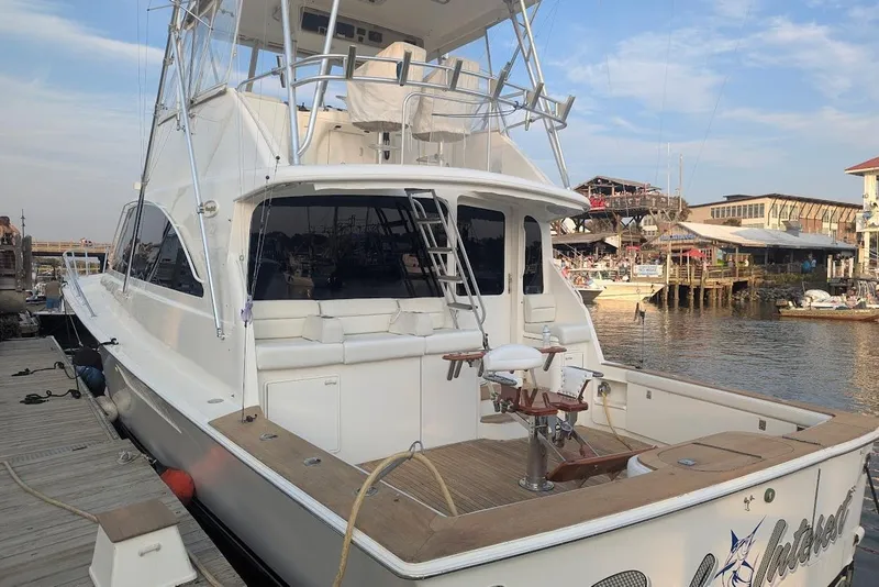 Slide: The Image of Ocean Yachts 56 Super Sport 2002 docked at marina, featuring spacious deck and fishing chair. - 81