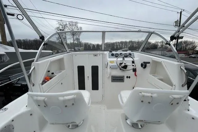 Slide: The Image of 2005 Sea Fox 230 Walk Around boat interior with dual captain chairs and steering console. - 9